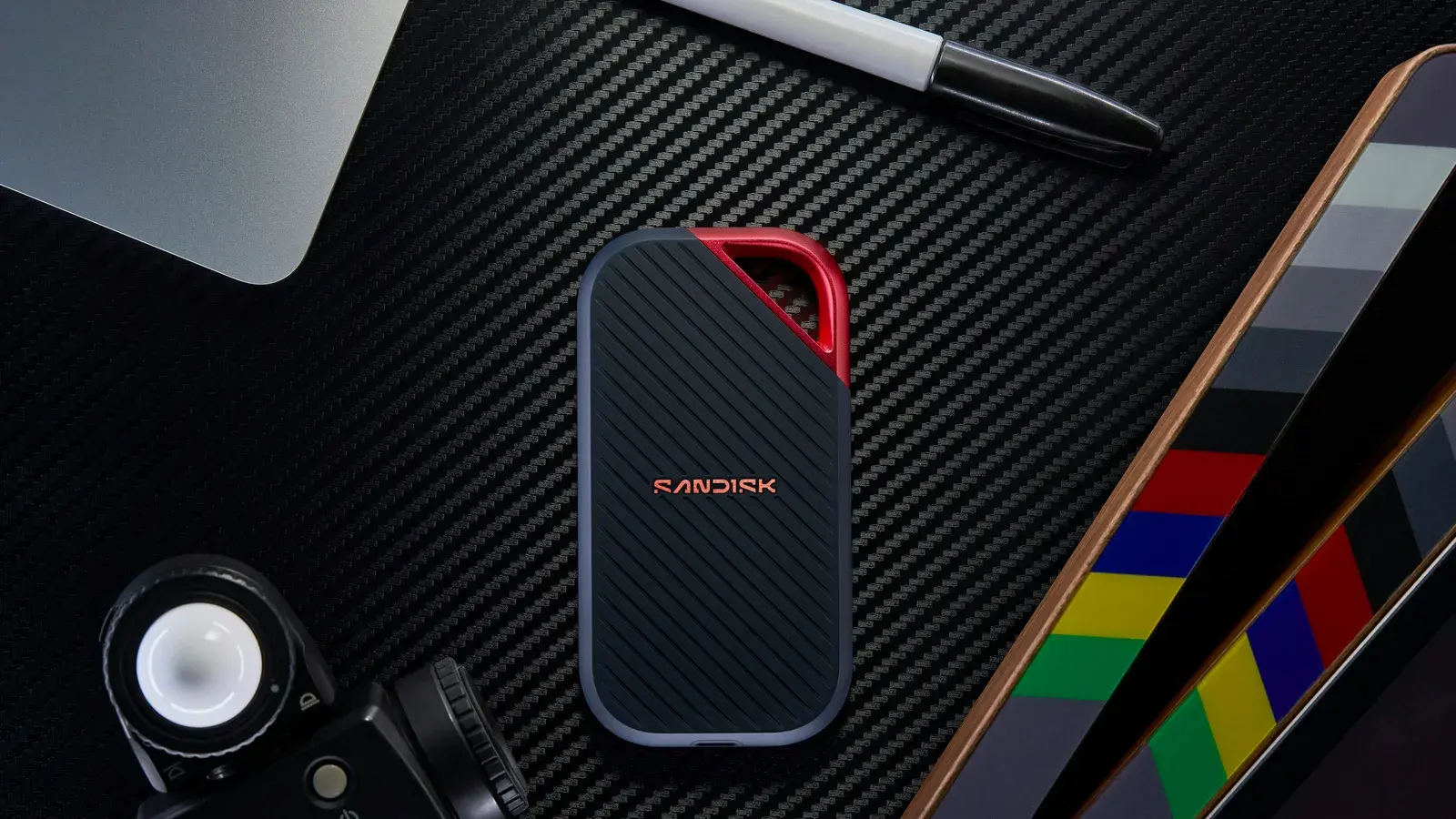 Portable SSD and cable on a carbon-fibre surface