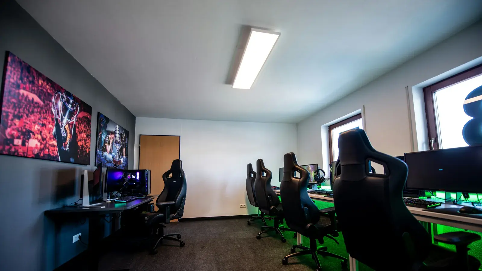 Long gaming room lined with PCs and chairs