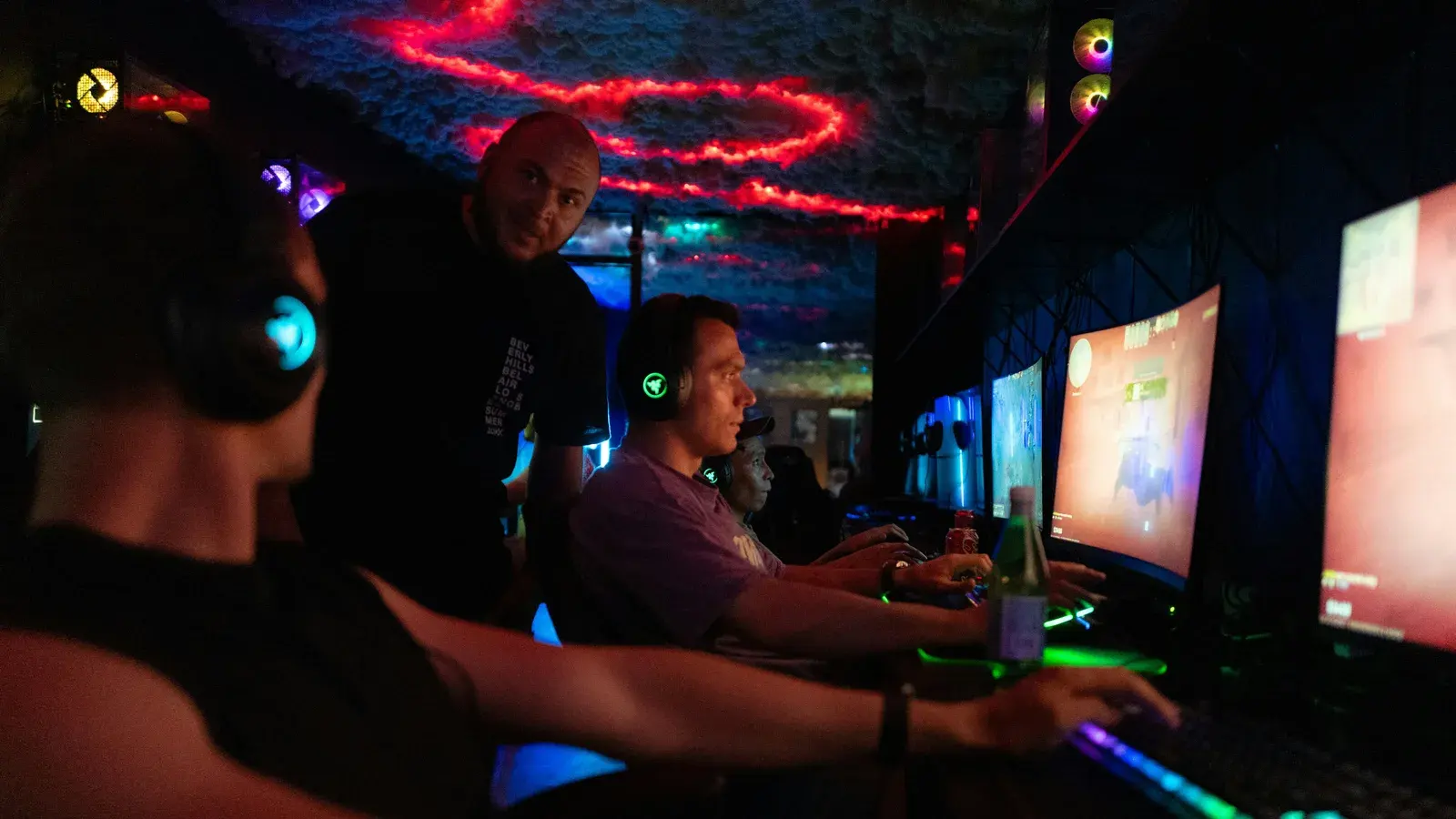 Players at desks ringed by red and blue neon light tubes