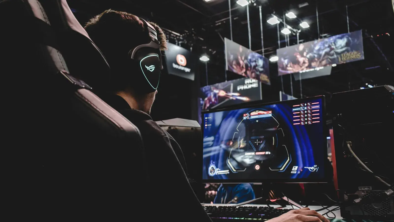 Player in a headset at an esports event with stage screens behind