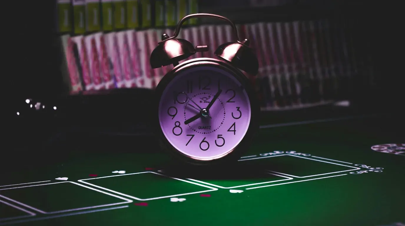 Vintage alarm clock standing on a dark green card table