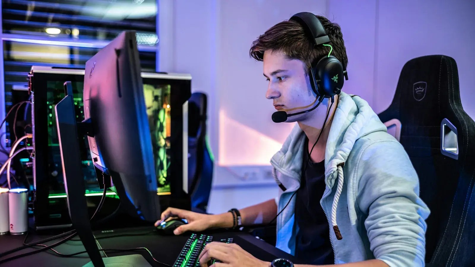 Player in a grey hoodie and headset at a tournament monitor
