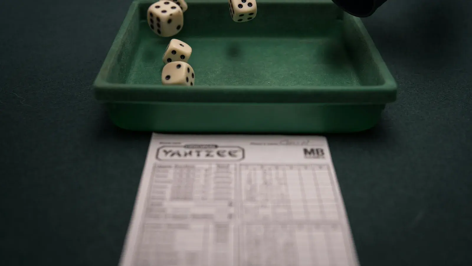 Five dice in a tray beside a Yahtzee scoresheet