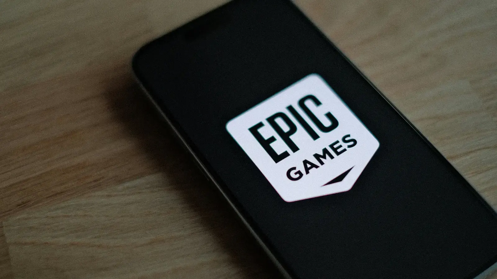 Smartphone on a wooden desk displaying the Epic Games logo