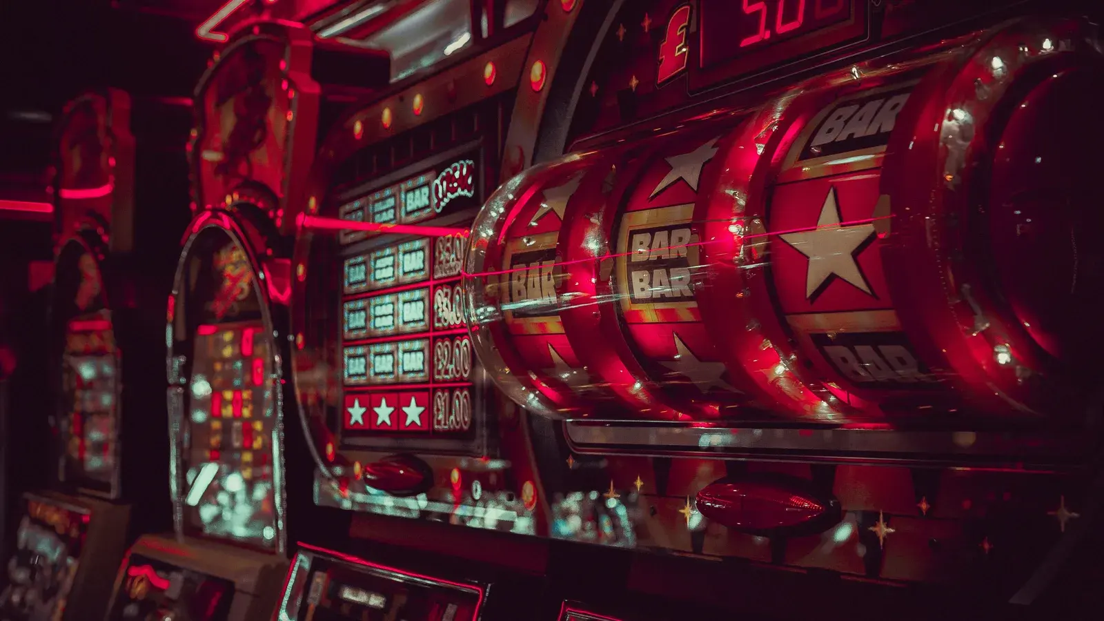 Row of red-lit slot machines showing bar and star symbols