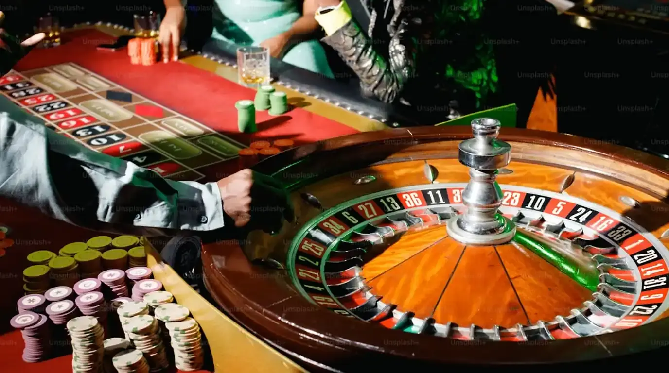 Roulette wheel and stacked chips with players around the table