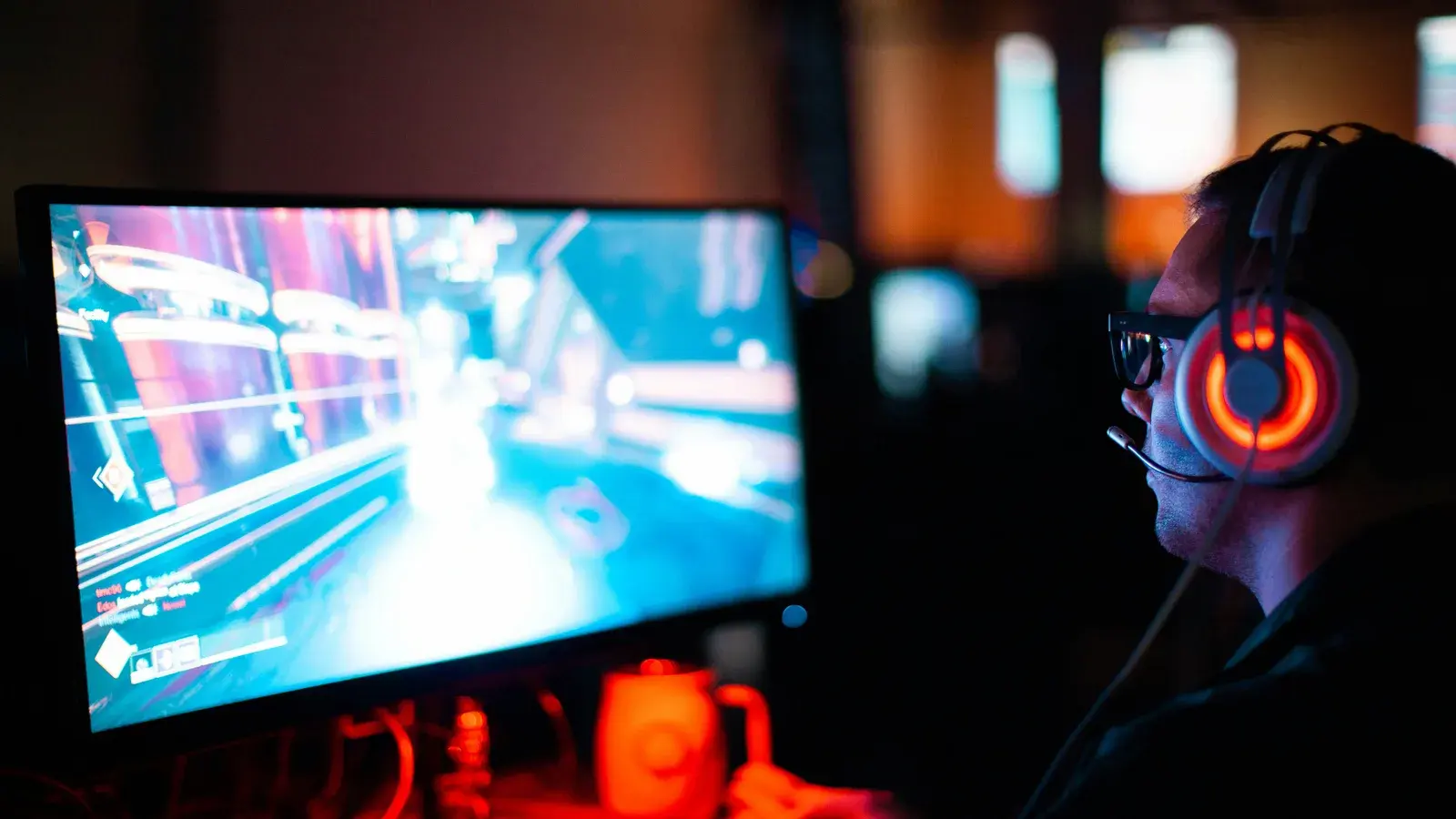 Game running on a monitor beside a red-lit headset in the dark
