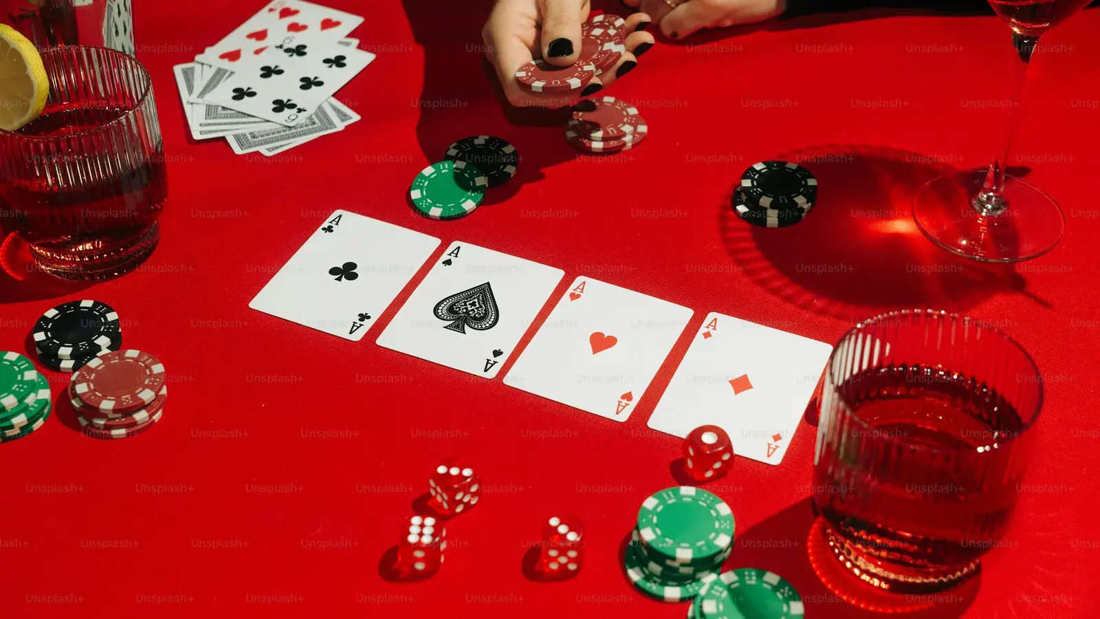 Poker hand of aces and chips on a red table