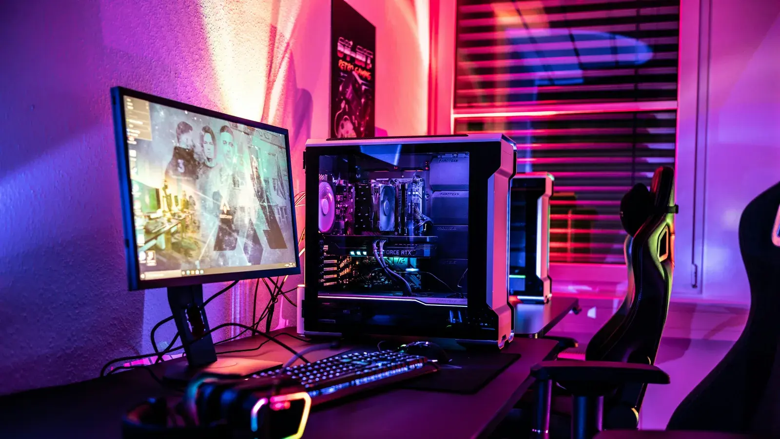 Monitor showing a game beside a purple-lit PC tower