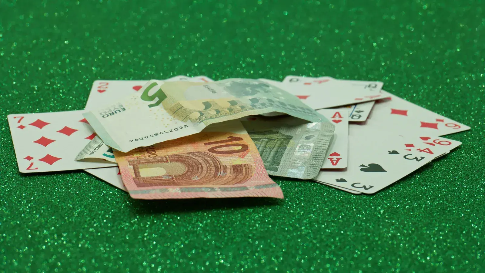 Playing cards and euro banknotes on green felt