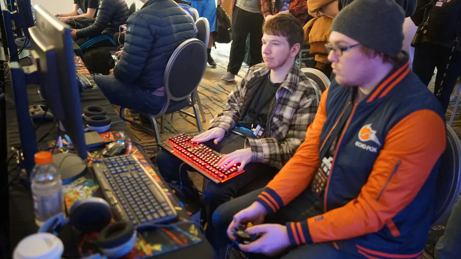 Two young players at a LAN event with keyboards and a controller