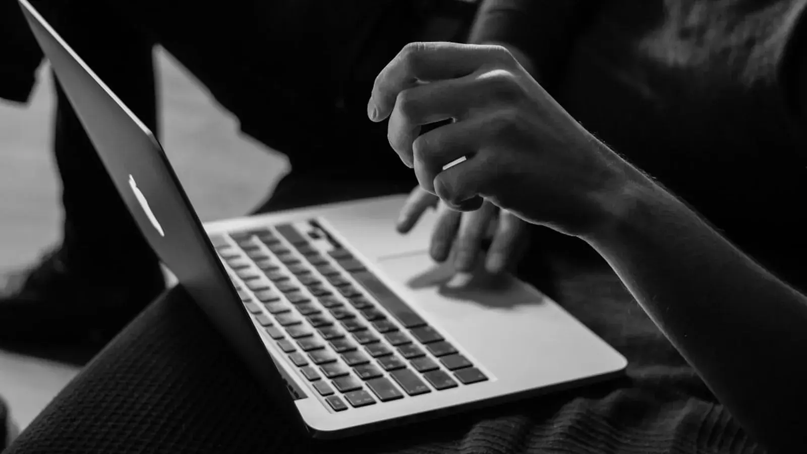 Hands typing on a laptop, black and white