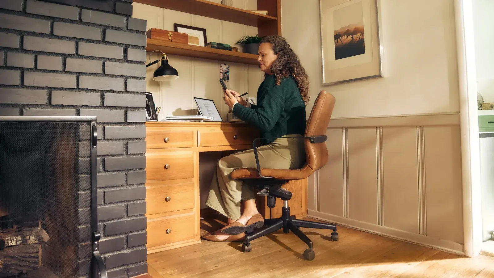 Woman at a home desk with a laptop and phone