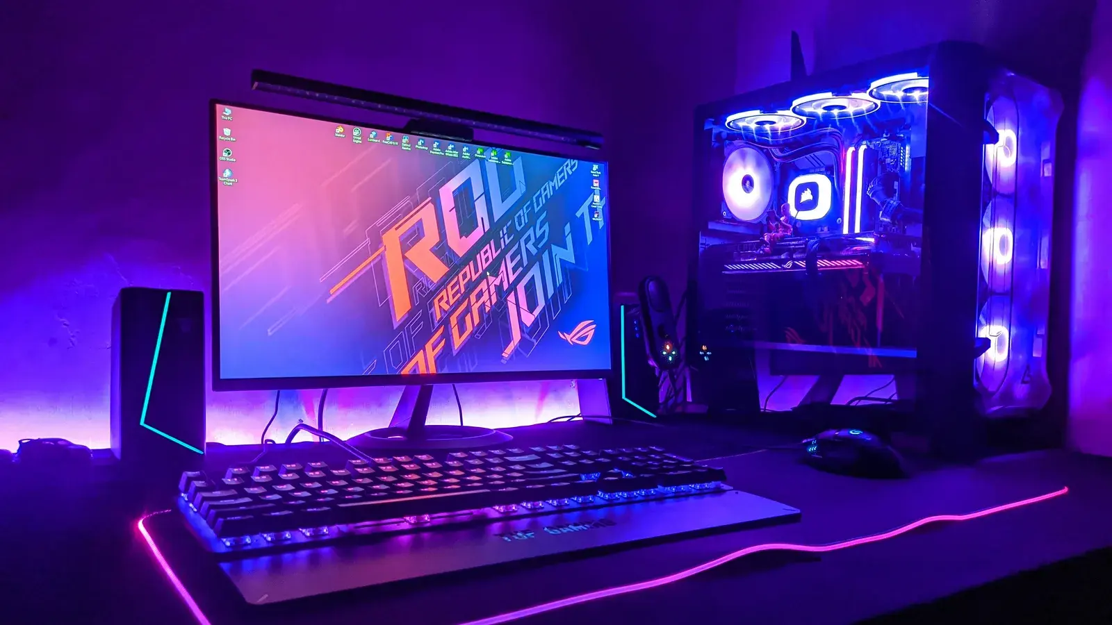 Purple-lit desk with an ROG monitor and a glass PC