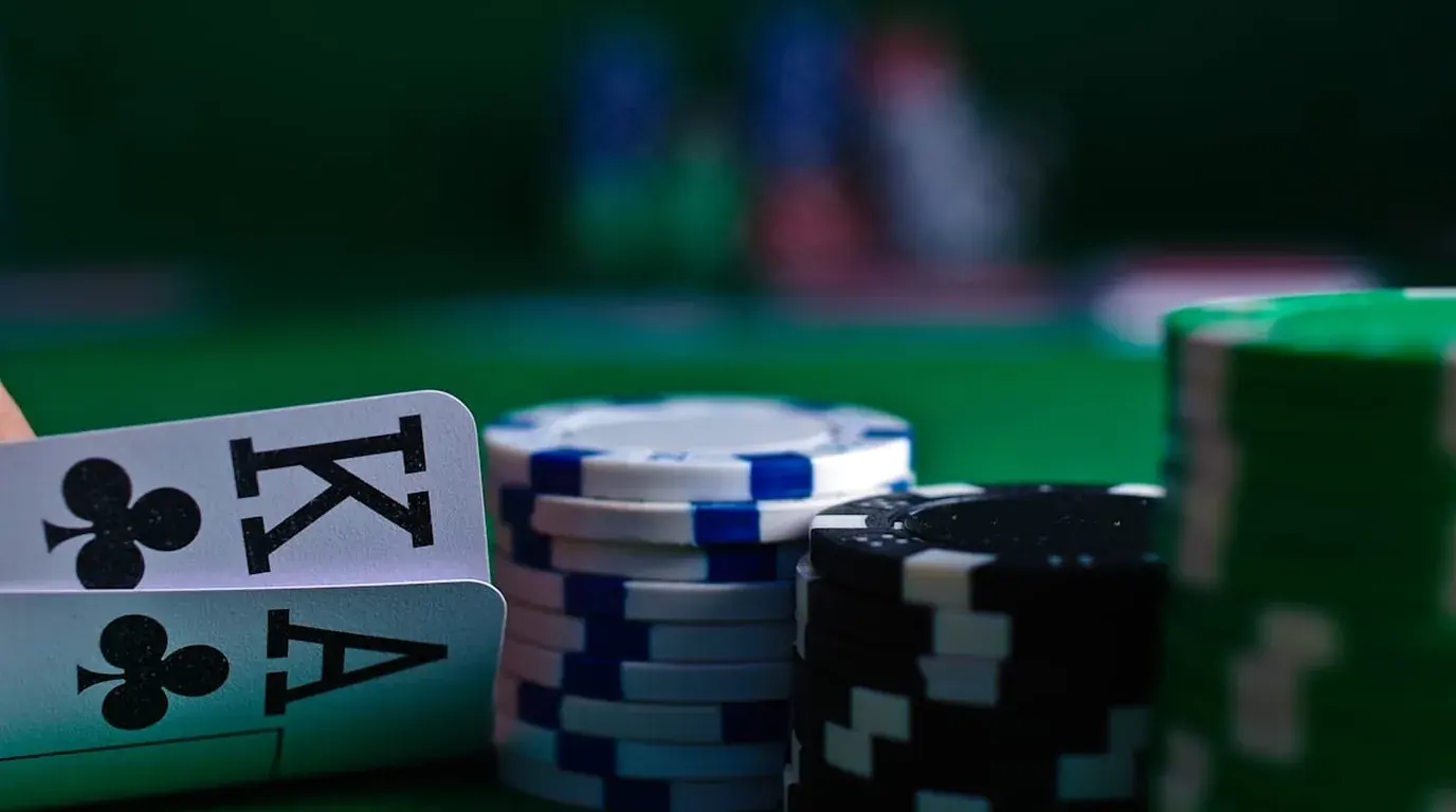 King and ace of clubs propped beside stacked chips on green baize