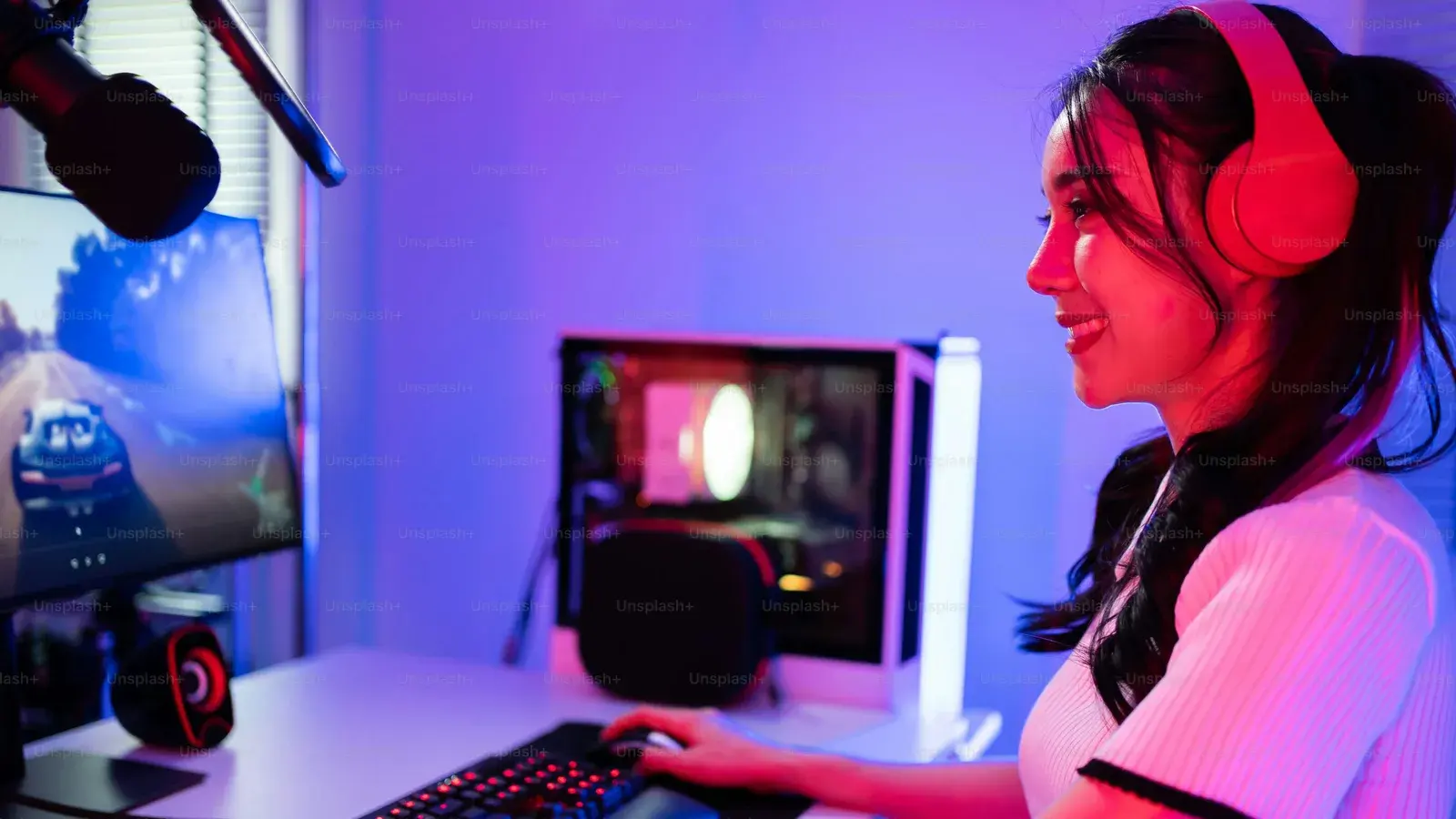 Woman in a red headset at a blue-lit gaming PC
