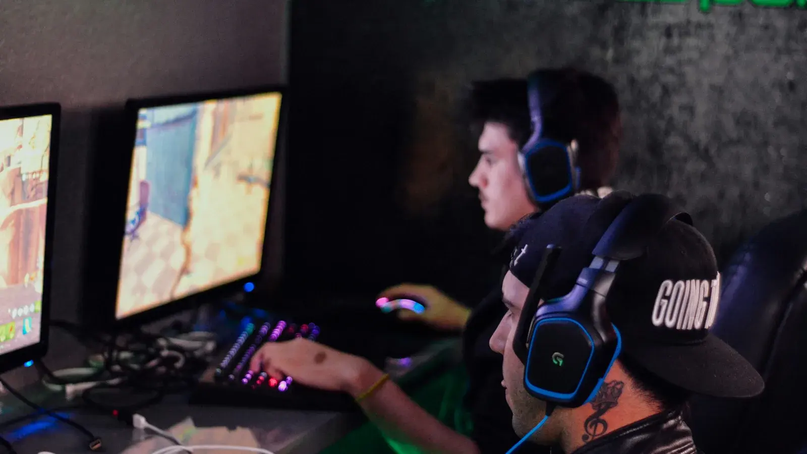 Player in a cap and blue headset at a monitor in darkness