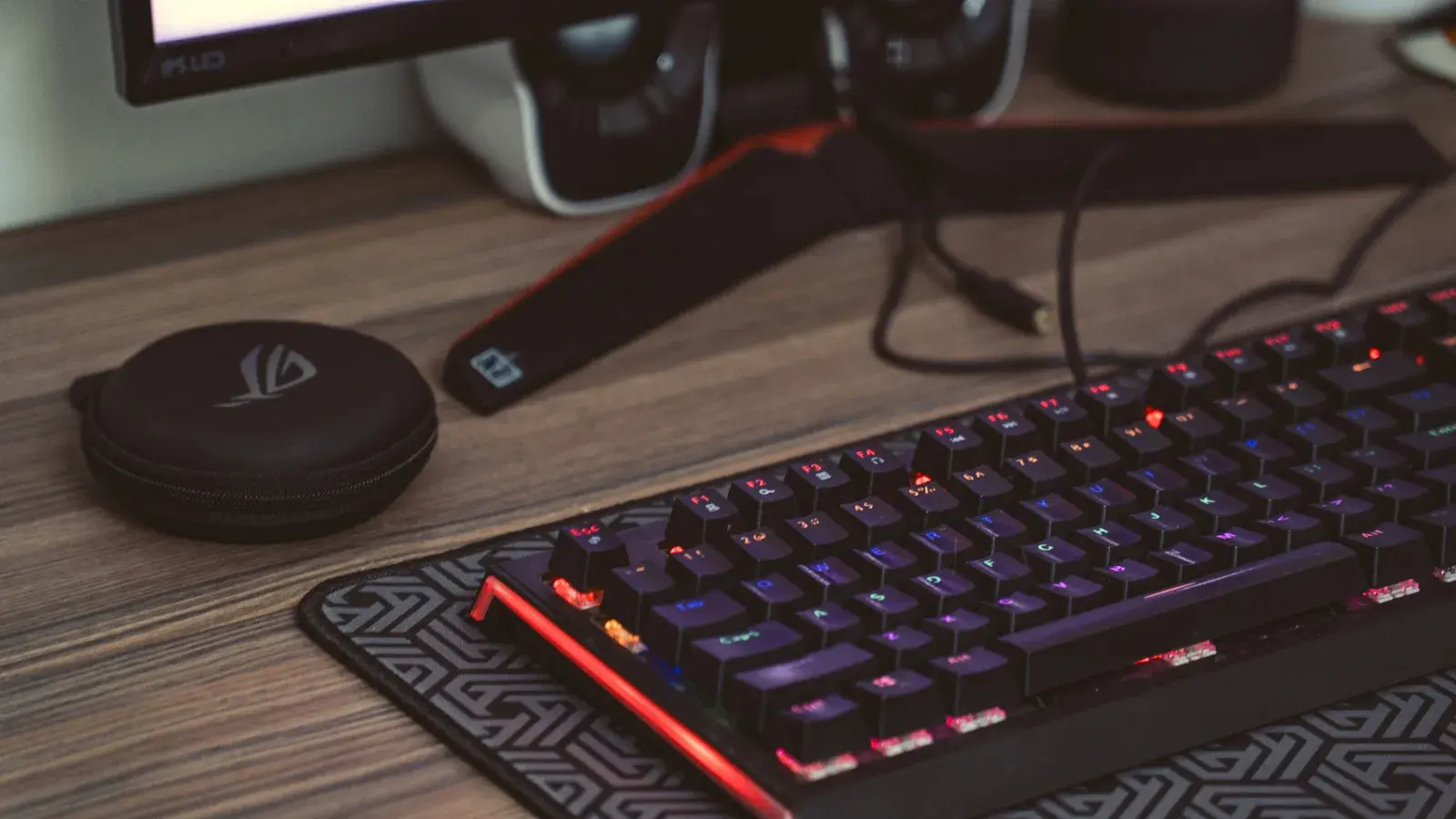 Red-lit mechanical keyboard and mouse on a wooden desk