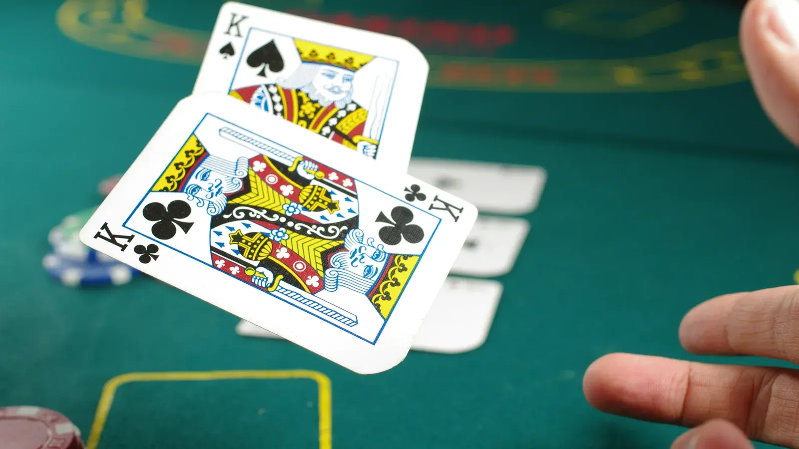 Two kings dealt face up over green felt beside a chip
