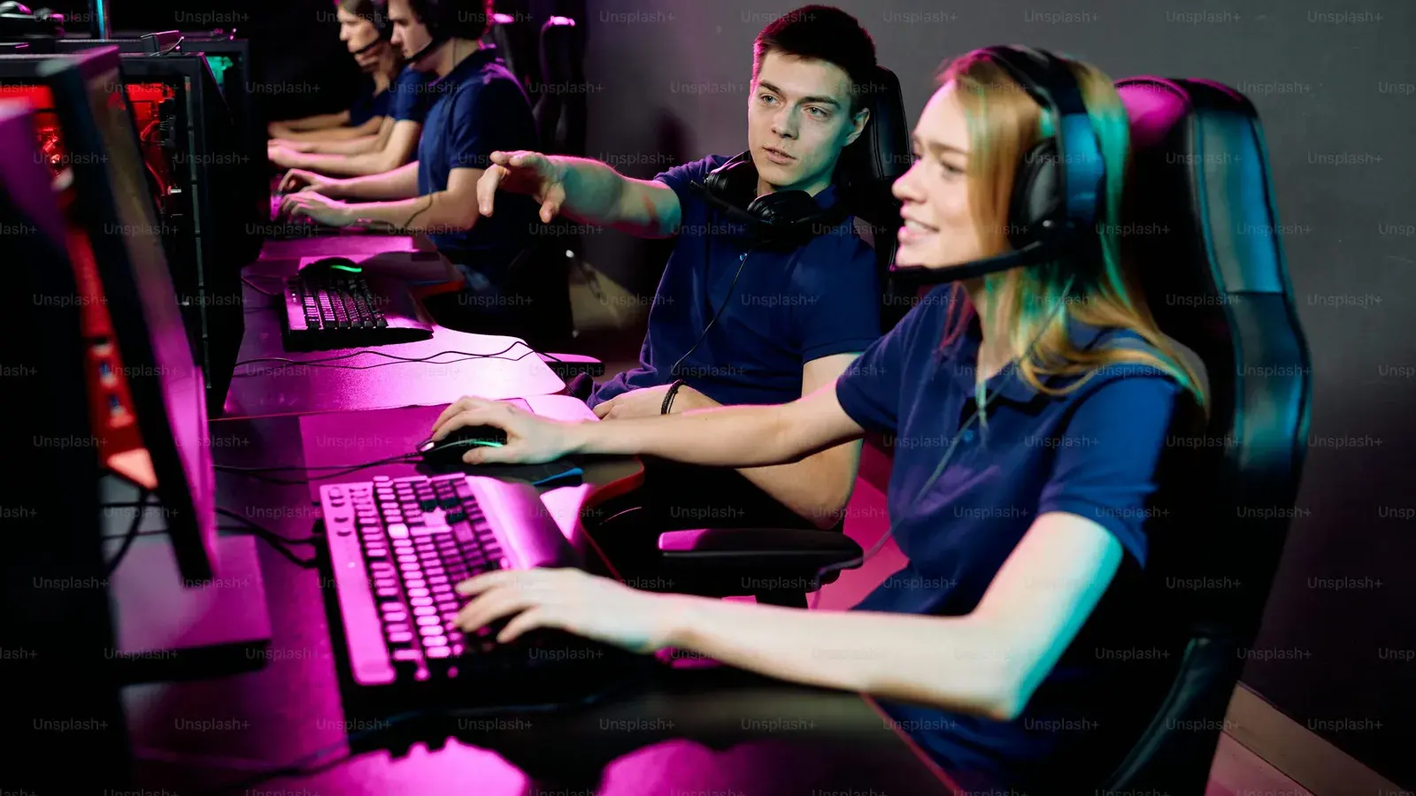 Two players side by side at a magenta-lit desk