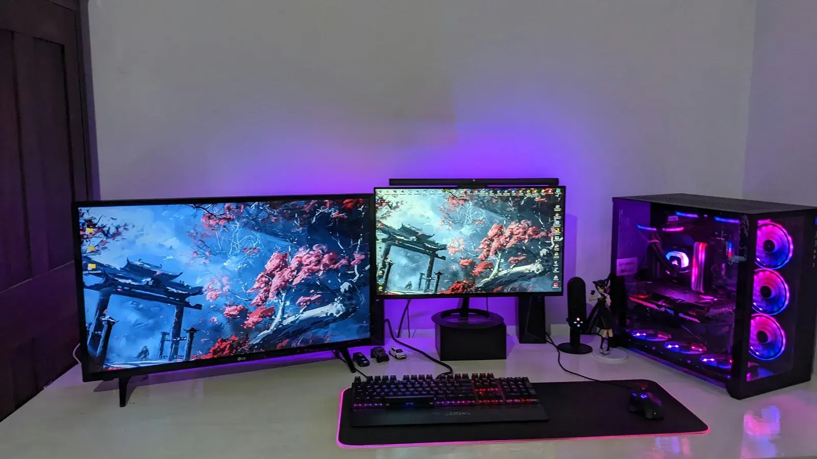 Two monitors, keyboard, mic and a purple-lit PC on a desk