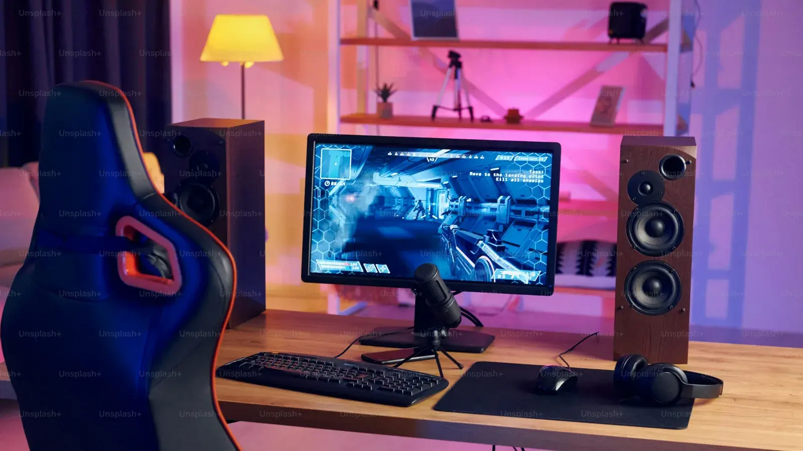 Pink-lit room with a monitor, speakers and gaming chair