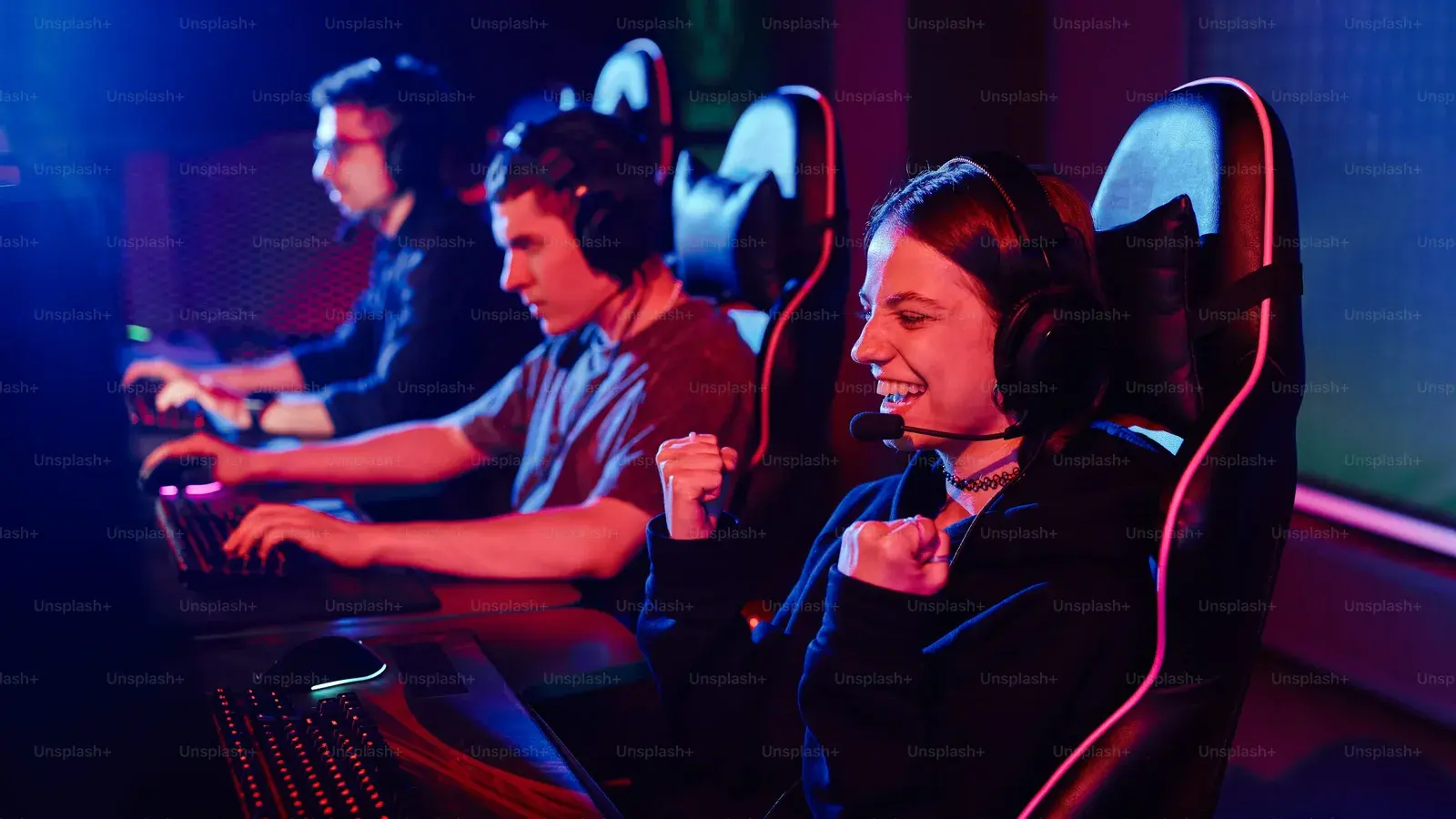 Three players in headsets side by side at a lit LAN row