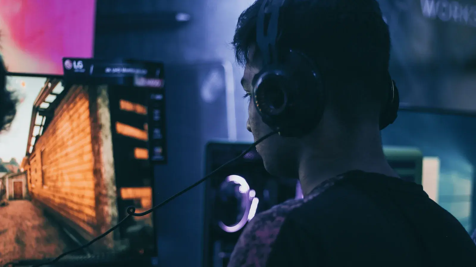 Player seen from behind in a headset facing a lit game monitor
