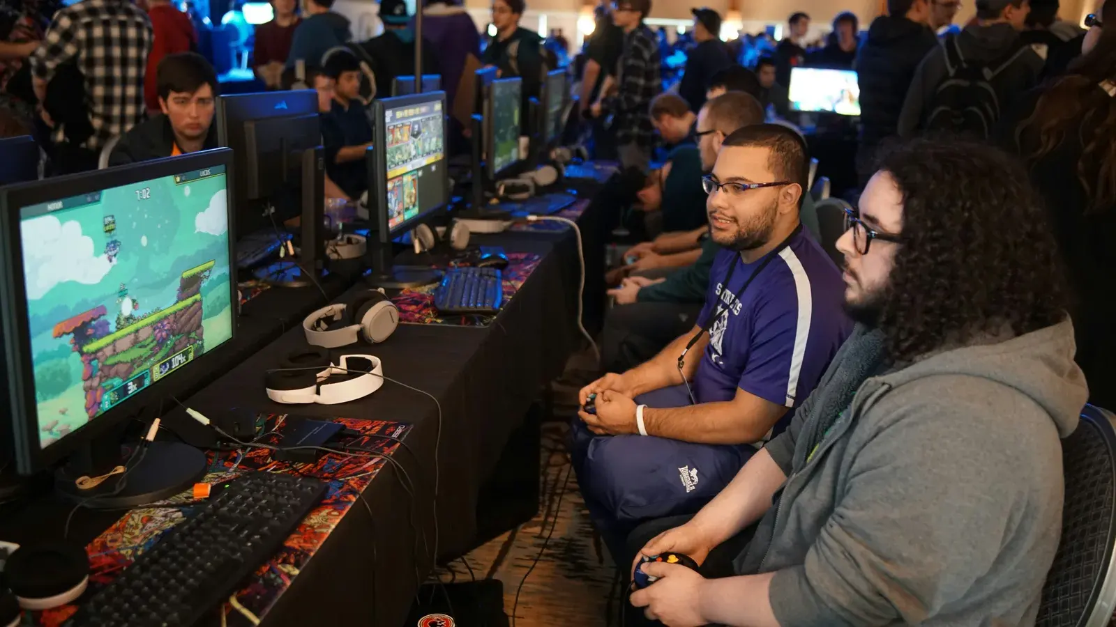 Crowded LAN hall with rows of players at monitors and keyboards