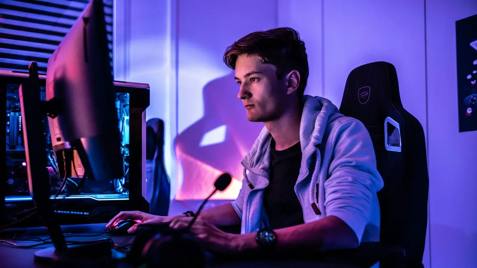 Man at a microphone and monitor in a blue-lit room